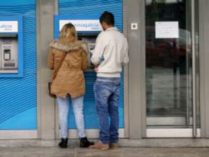 Dos clientes retiran dinero de un cajero de NCG Banco en A Coru&ntilde;a. 