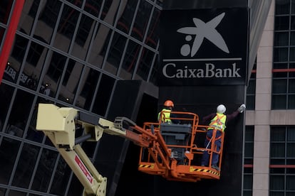 Dos operarios instalan el 27 de marzo el logo de CaixaBank, en el edificio de la sede de Bankia, en las torres Puerta de Europa de Madrid.