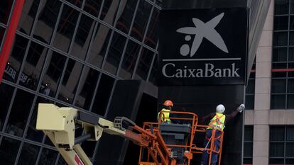 Workers putting up a CaixaBank sign at Bankia headquarters in Madrid's Puerta de Europa towers following the merger.