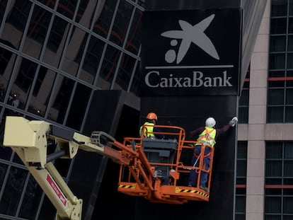 Workers putting up a CaixaBank sign at Bankia headquarters in Madrid's Puerta de Europa towers following the merger.