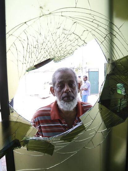 Un hombre observa el interior de un establecimiento atacado.