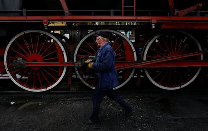 Un hombre camina cerca de una locomotora de vapor después del desfile.