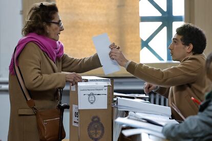 Una mujer recibe el material electoral para su votación.