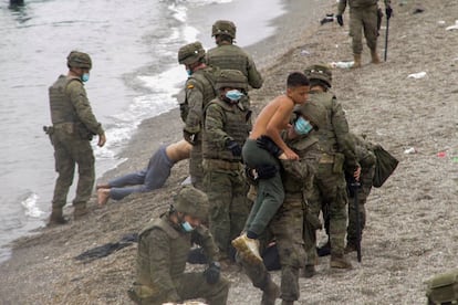 Miembros del Ejército de Tierra ayudan a un grupo de inmigrantes que han logrado cruzar uno de los espigones fronterizos de Ceuta este martes. 