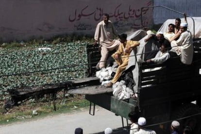 Paquistaníes subidos a bordo de un camión que transporta los restos de un helicóptero del ejército de EEUU que se estrelló durante la operación.