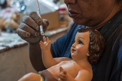 Un artesano restaura una mano de un niño Dios.