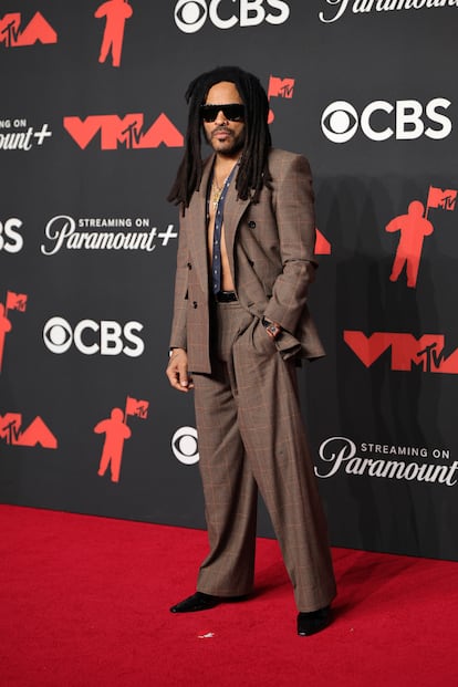 Lenny Kravitz, con traje marrón sin camisa y sus inseparables gafas de sol.
