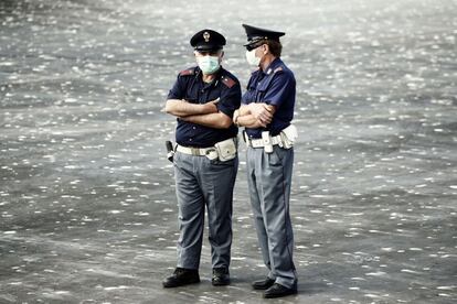 Dos policías con mascarilla esperan a los migrantes a primera hora de la mañana en Porto Empedocle (Sicilia)."No me asustan [los agentes]", responde seguro un nigeriano desde la cubierta principal del Dignity I.