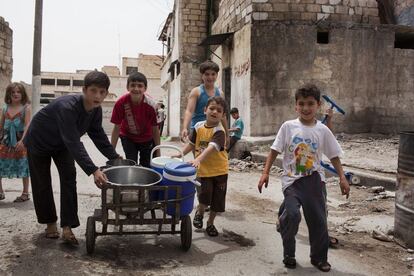 Un grupo de niños del barrio de Bustan Al-Qaser, en Alepo, lleva recipientes con agua repartida en distintos puntos de la ciudad ante la escasez que azota la ciudad.