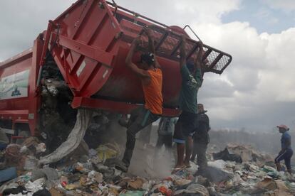 Migrantes venezolanos saltan a un camión en un basurero en la ciudad fronteriza de Paramaima (Brasil), el 13 de abril de 2019.