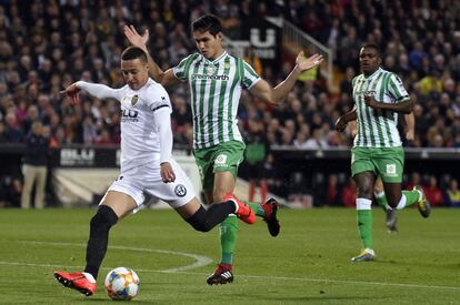 El delantero del Valencia, Rodrigo, dispara a puerta tras superar al defensa del Betis, Aissa Mandi.