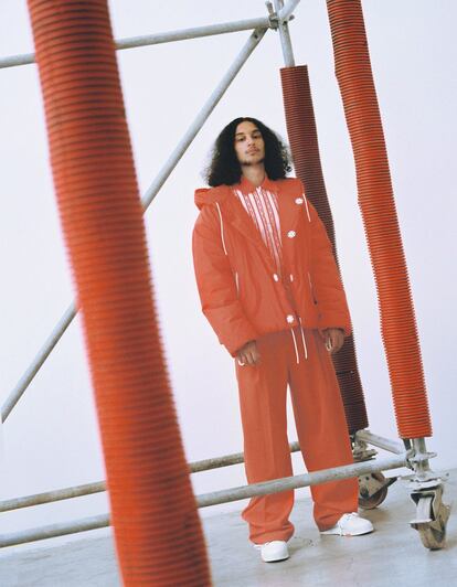 Anorak acolchado con piezas metálicas, polo con estampados de cadenas, pantalón rojo en tejido técnico y deportivas Trainer Sneaker, todo de Louis Vuitton.