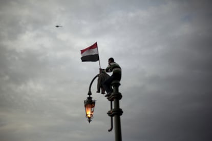 Un  manifestante, subido a una farola, protesta contra el régimen de Mubarak en la plaza Tahrir, en el centro de El Cairo. Muchos siguieron las convocatorias a través de Internet.