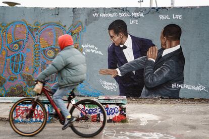 Un ciclista pasa, el 1 de abril, por un mural pintado en una calle de Berlín que escenifica el bofetón de Will Smith a Chris Rock. La obra es del artista dominicano Jesús Cruz Artiles.  