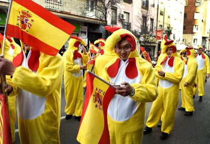 Participantes en el desfile vestidos de gallo y portando banderas de España.