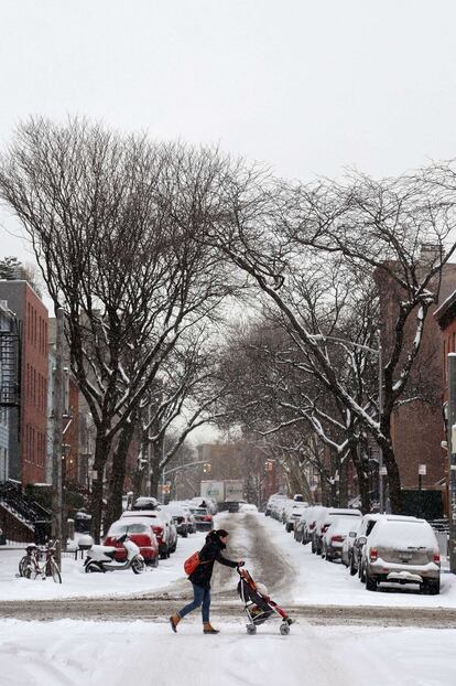 NEW YORK, NY - FEBRUARY 17: A woman pushes a child in a stroller across the street as it snows on February 17, 2015 in New York City. Winter storm Octavia brought snow and cold temperatures to much of the east coast. Michael Heiman/Getty Images/AFP == FOR NEWSPAPERS, INTERNET, TELCOS & TELEVISION USE ONLY ==