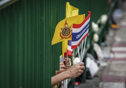 Tailandeses muestran banderas nacionales mientras aguardan la salida del cortejo fúnebre del rey Bhumibol Adulyadej desde el hospital Siriraj en Bangkok (Tailandia).