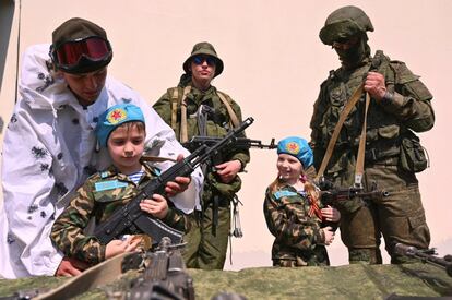 Un niño y una niña vestidos con uniforme militar cogen dos armas durante un desfile de soldados organizado en las escuelas en honos a los veteranos de la Segunda Guerra Mundial para conmemorar el Día de la Victoria, en Rostov-on-Don (Rusia).