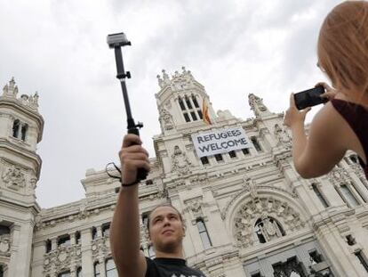 Dos jóvenes toman fotos del Ayuntamiento con la pancarta de apoyo a los refugiados.