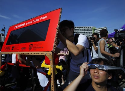 Miles de personas se lanzaron a las calles para compartir la visión del fenómeno. En la imagen, habitantes de Hong Kong se protegen los ojos para poder mirar al Sol en el inicio del eclipse.