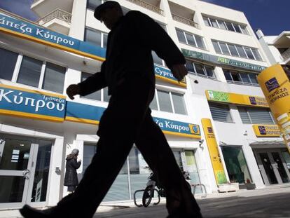 Un ciudadano pasa entre el Banco de Pireo, a la derecha, y el Banco de Chipre, en Atenas