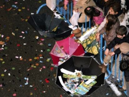 Los niños recogen caramelos con paraguas durante la Cabalgata de los Reyes Magos de Madrid.