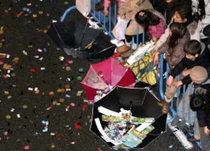 Los niños recogen caramelos con paraguas durante la Cabalgata de los Reyes Magos de Madrid.