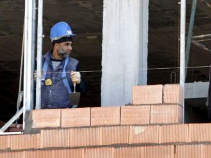 Tres obreros trabajan en la construcci&oacute;n de una vivienda. 