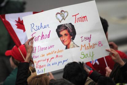 Miembros del público que siguió la boda desde la calle levantan un cartel con la fotografía de Diana de Gales.
