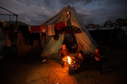 Un grupo de palestinos desplazados entra en calor frente a un fuego cerca de su tienda de campaña este martes en Rafah (sur de Gaza).