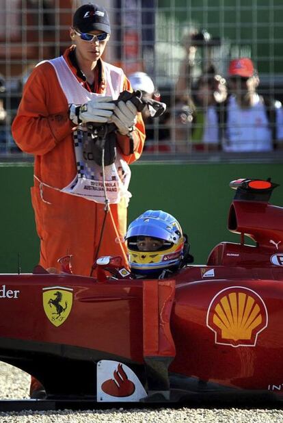 Un oficial de pista ayuda al piloto español Fernando Alonso, que acabó en la gravilla durante la sesión de clasificación.