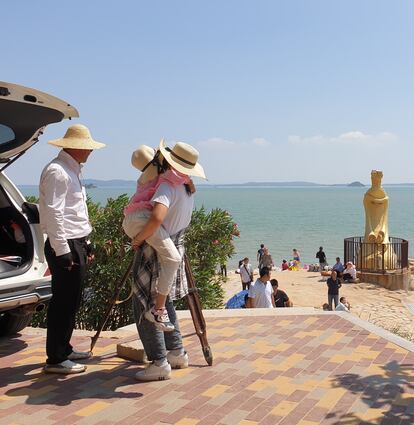 Una mujer mira por un catalejo las islas taiwanesas de Kinmen desde la playa en Xiamen (China)