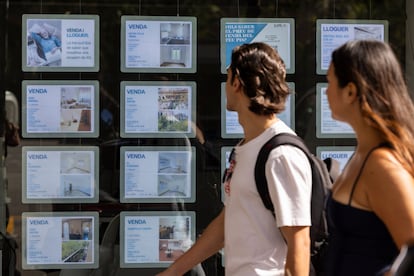 Dos personas pasan frente a una inmobiliaria en Barcelona.