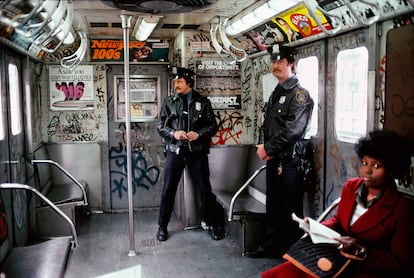 Dos agentes de policía y una pasajera viajando en 1981 en un vagón del metro de Nueva York cubierto de pintadas.