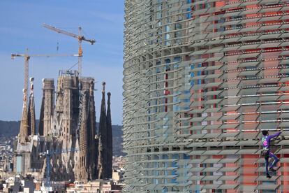 El escalador urbano francés Alain Robert escala los 144 metros de la torre de las Glorias en Barcelona. Al fondo, la basílica de la Sagrada Familia diseñada por el arquitecto Antoni Gaudí.