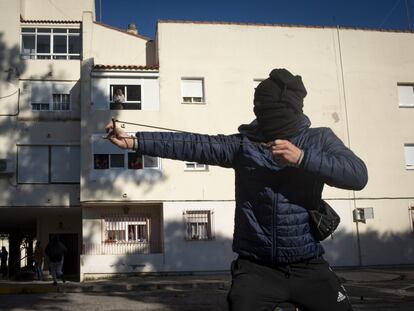 Un manifestante encapuchado ataca a la policía con un tirachinas.