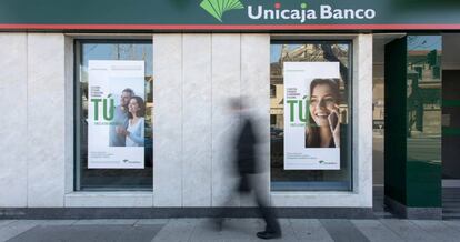 Una persona pasa por delante de una sucursal de Unicaja Banco.