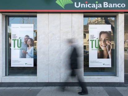 Una persona pasa por delante de una sucursal de Unicaja Banco.