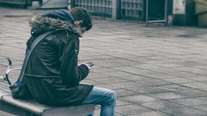 Un adolescente consulta un teléfono móvil.