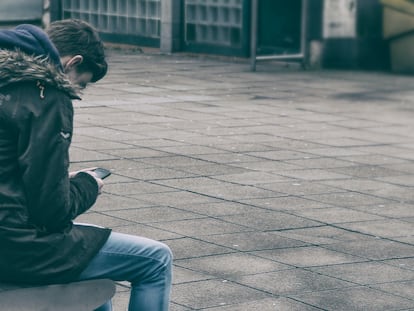 Un adolescente consulta un teléfono móvil.