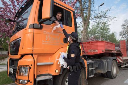 Un agente de policía reparte mascarillas en la entrada del polígono industrial de la Magantina de Huesca.