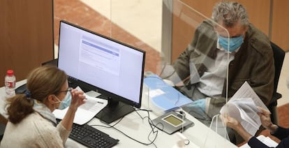 Una trabajadora de la Oficina de la Agencia Tributaria en la Calle Guzmán el Bueno atiende a un hombre el día en el que la atención presencial en oficinas de la Agencia Tributaria para confeccionar la declaración de la Renta de 2019 se retoma.