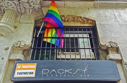 En la fachada del Dacksy convive la bandera multicolor con el cartel de traspaso.
