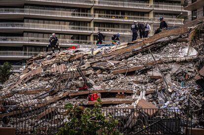 Miembros del equipo de búsqueda y rescate urbano del sur de Florida trabajan entre los escombros del edificio en Surfside, Florida. Decenas de rescatistas y bomberos trabajaban esta madrugada a destajo retirando escombros en busca de alguno de los casi 160 desaparecidos, muchos de ellos latinoamericanos.