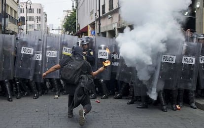 Un encapuchado lanza un c&oacute;ctel molotov a la polic&iacute;a.