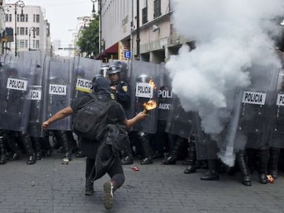 Un encapuchado lanza un c&oacute;ctel molotov a la polic&iacute;a.