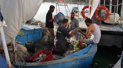 Cuatro pescadores recosen las redes antes de salir en alta mar en una de las barcas típicas de Katef, de tamaño medio.