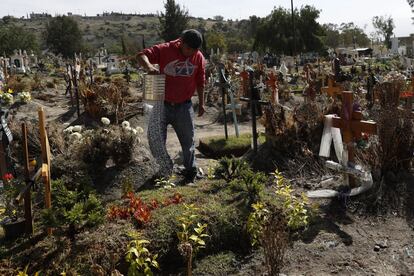 Un trabajador riega las plantas sobre una tumba del Cementerio Municipal del Valle de Chalco abierto hace dos meses para acoger el aumento de cadáveres fallecidos durante el coronavirus, en las afueras de la Ciudad de México.