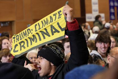 A man holds a banner as climate protesters interrupt the campaign event of Former U.S. President and Republican presidential candidate Donald Trump, in Indianola, Iowa, U.S., January 14, 2024. REUTERS/Brendan McDermid     TPX IMAGES OF THE DAY