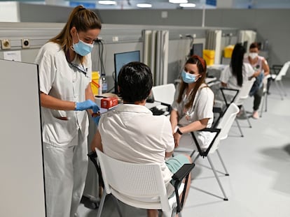 Dos enfermeras vacunan a un hombre en el Hospital Isabel Zendal de Madrid, en junio.